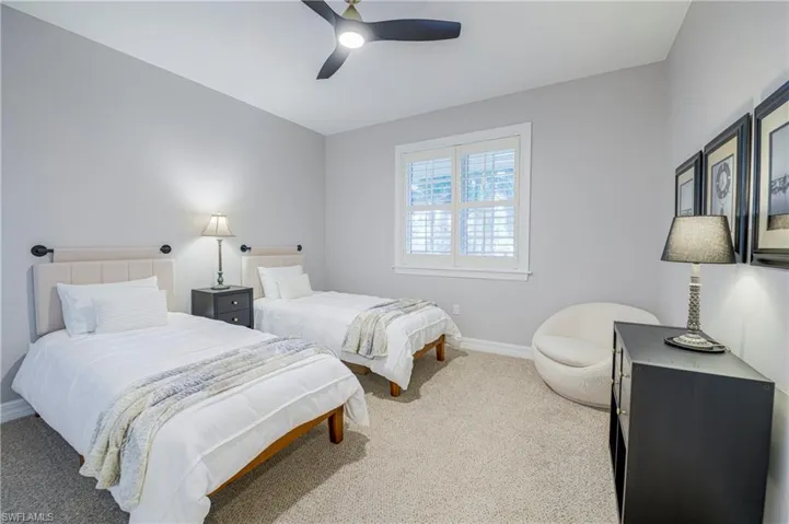 Carpeted room featuring a ceiling fan, light gray wall paint, and a window with white plantation shutters