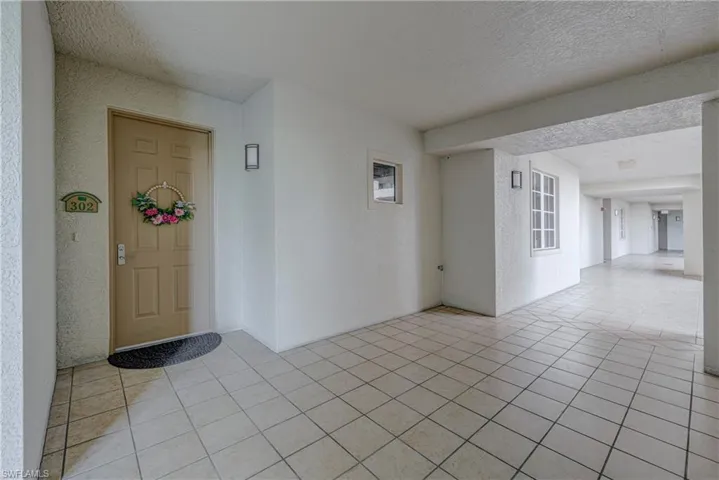 Entryway featuring a panel door with contemporary hardware, ceramic tile flooring, and wall-mounted sconce lighting