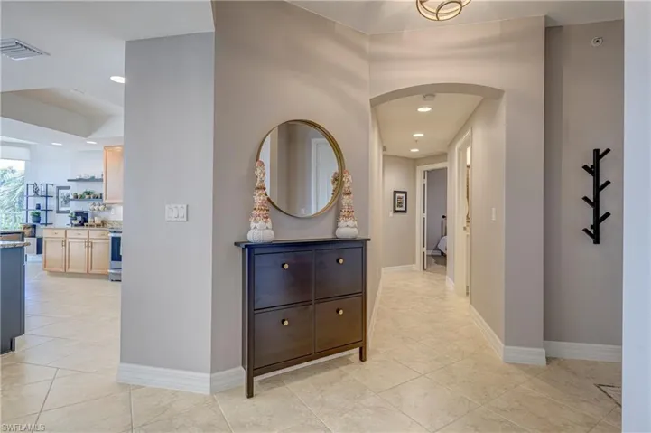 Hallway with tile flooring and recessed lighting, featuring an arched entryway and light neutral wall paint