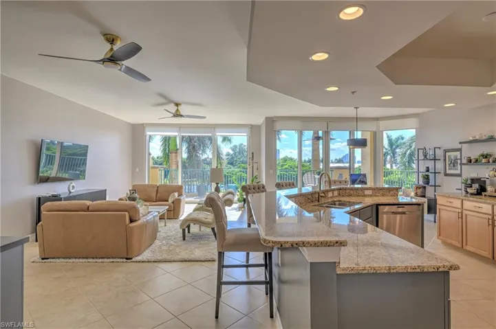 Open-concept living area featuring a kitchen with light-toned cabinetry, granite countertops, and stainless steel appliances