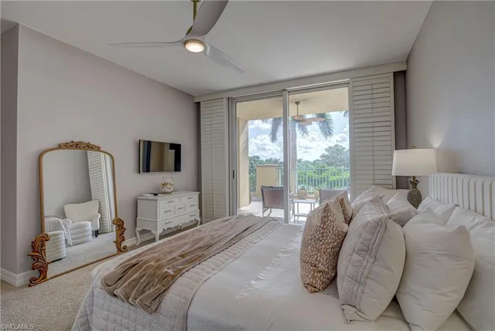 Bedroom with private balcony access, sliding glass doors, plantation shutters, and a ceiling fan with integrated lighting