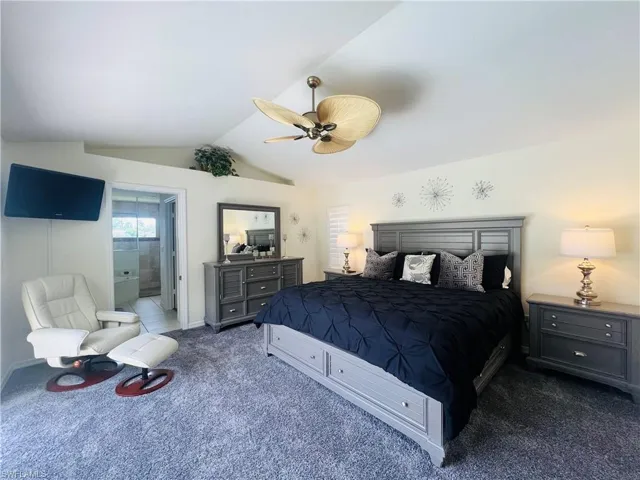 Bedroom featuring ensuite bathroom, with grey carpet, ceiling fan, and lofted ceiling