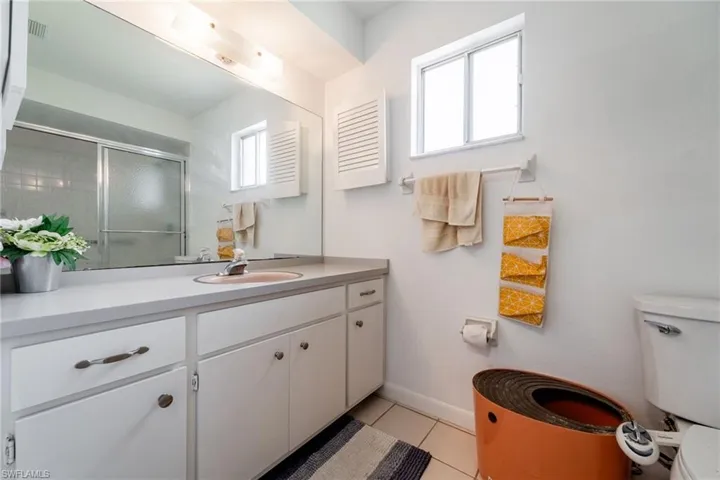 Bathroom with vanity, light tile patterned floors, and a stall shower