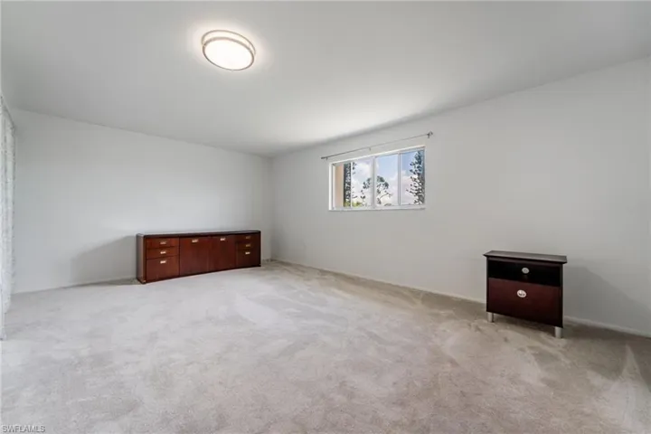 Unfurnished bedroom featuring light carpet and baseboards