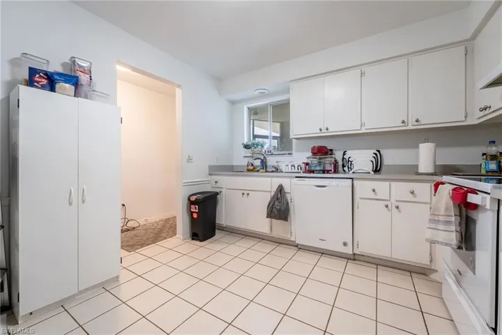 Kitchen with white cabinets, white appliances, light countertops, and light tile patterned floors