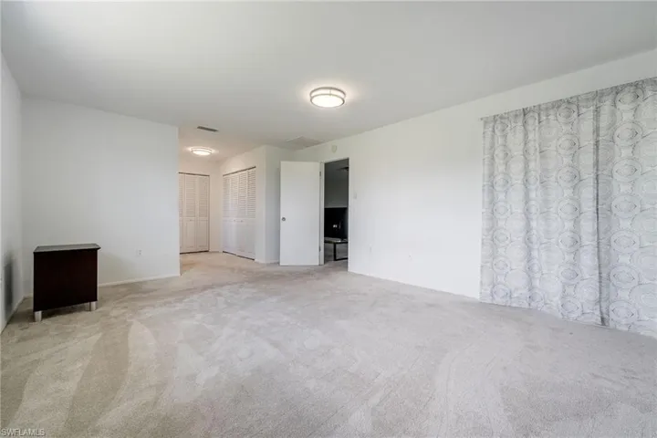 Unfurnished bedroom featuring light colored carpet and two closets