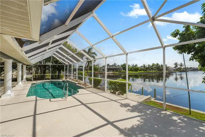 Screened lanai with a swimming pool, concrete decking, and waterfront access