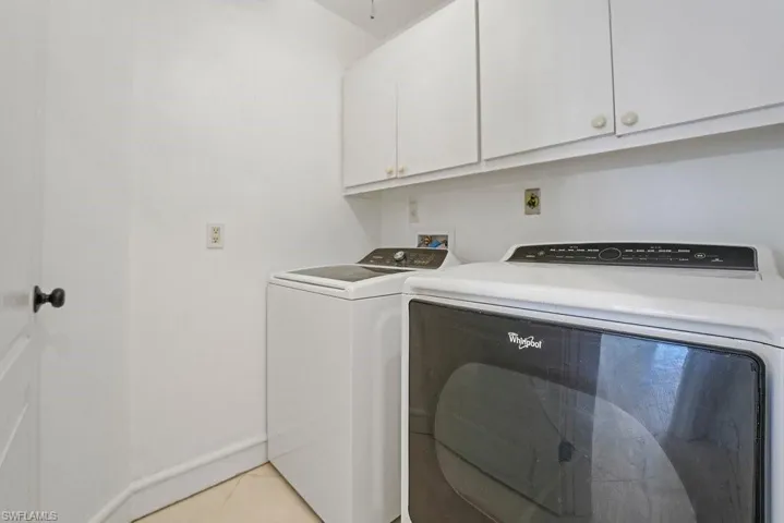 White cabinetry with knob hardware, light-toned flooring, and a solid white door