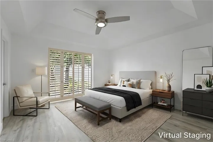 Tray ceiling with a ceiling fan, wood-finish flooring, and white plantation shutters