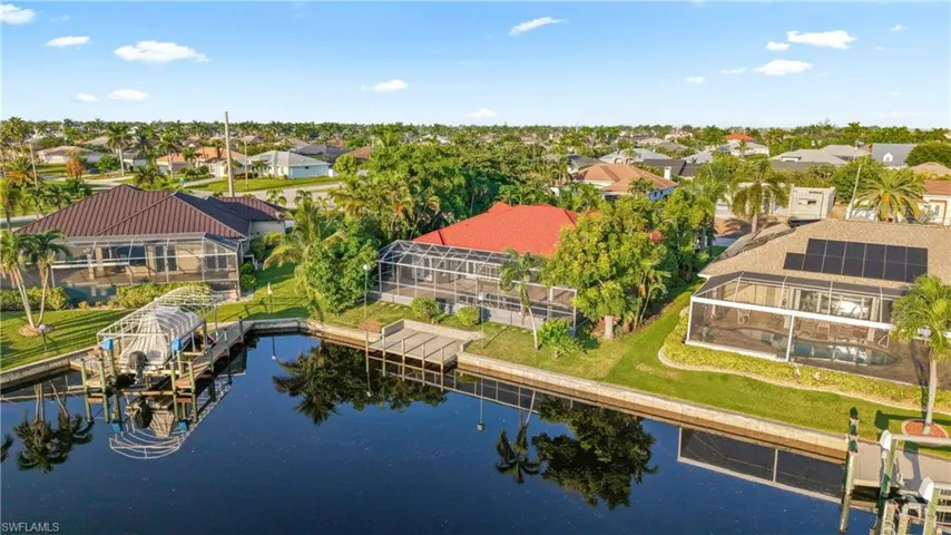 Waterfront property with canal access, screened patio, established landscaping, and a boat dock
