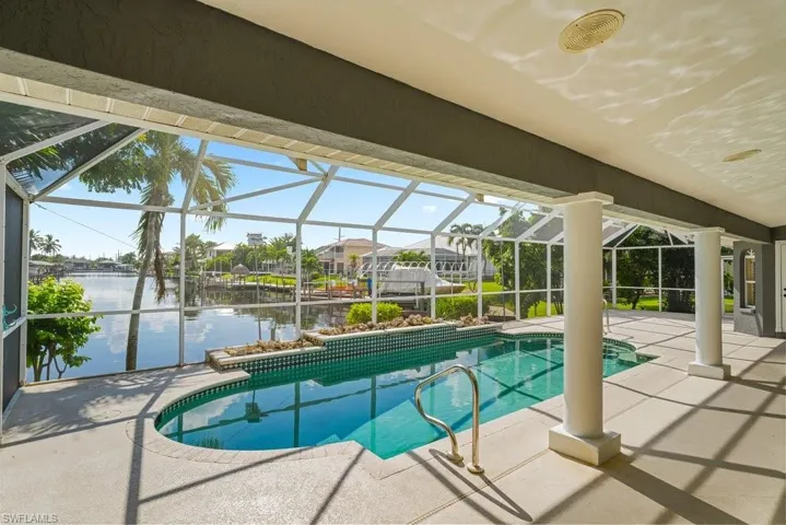 Screened lanai featuring a swimming pool, integrated spa, and waterfront setting