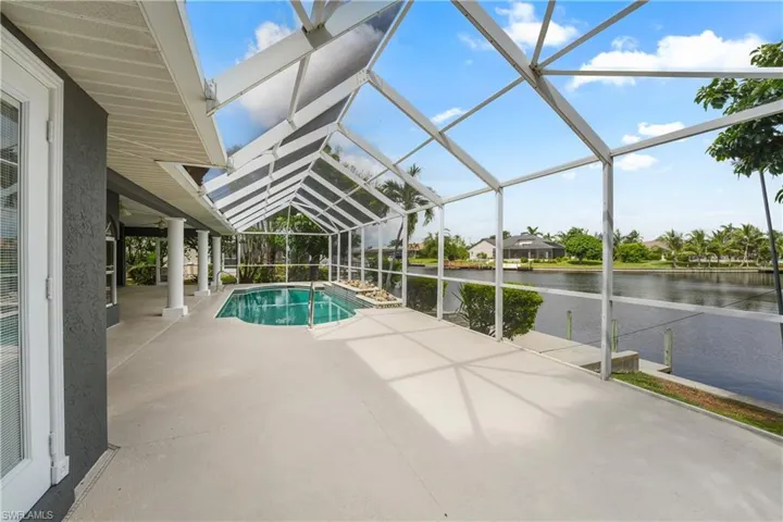 Screened outdoor living area with a built-in swimming pool and direct water frontage