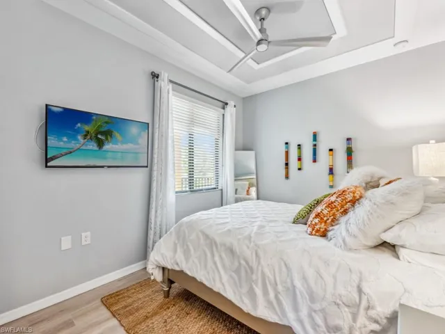 Guest bedroom featuring a tray ceiling, ceiling fan, and hardwood / wood-style flooring