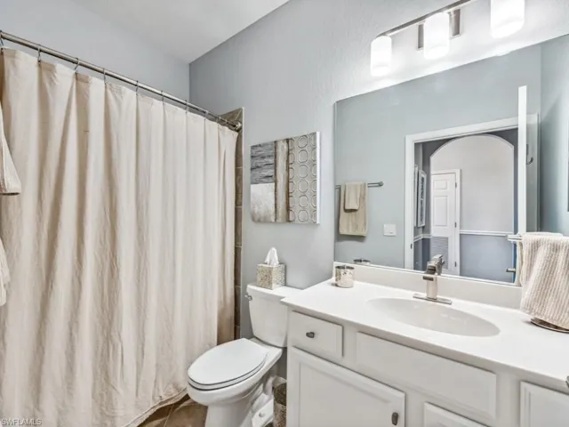 Guest bathroom with vanity, toilet, and curtained shower