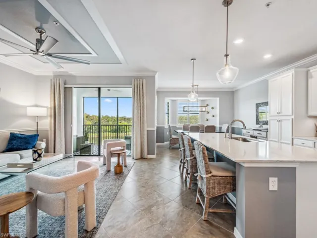 Kitchen with white cabinetry, a breakfast bar, pendant lighting, a kitchen island with sink