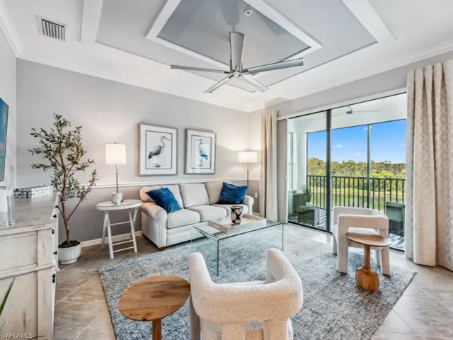 Living room with water view featuring ceiling fan, crown molding, and light tile patterned floors
