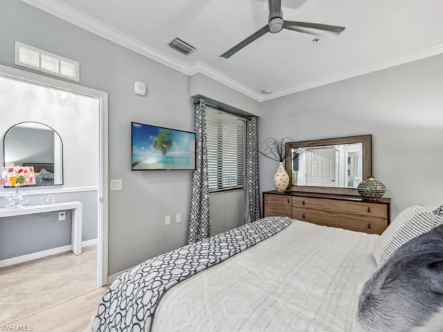 Primary bedroom with ceiling fan, light wood-type flooring, and ornamental molding