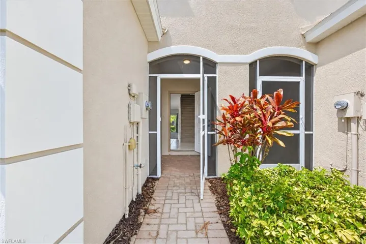 Entryway featuring a paver walkway, arched screen door, and stucco exterior