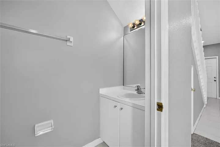 Vanity with an integrated sink and base cabinetry, complemented by a wall-mounted mirror with overhead lighting