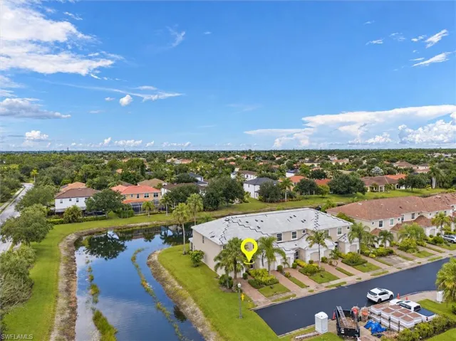Townhome property featuring a canal frontage, mature palm trees, and multiple parking spaces