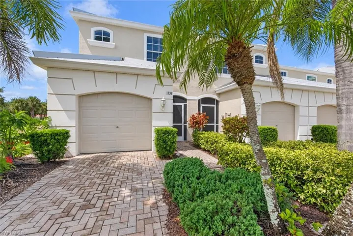 Stucco exterior with arched windows, an arched entry door, and a paver driveway