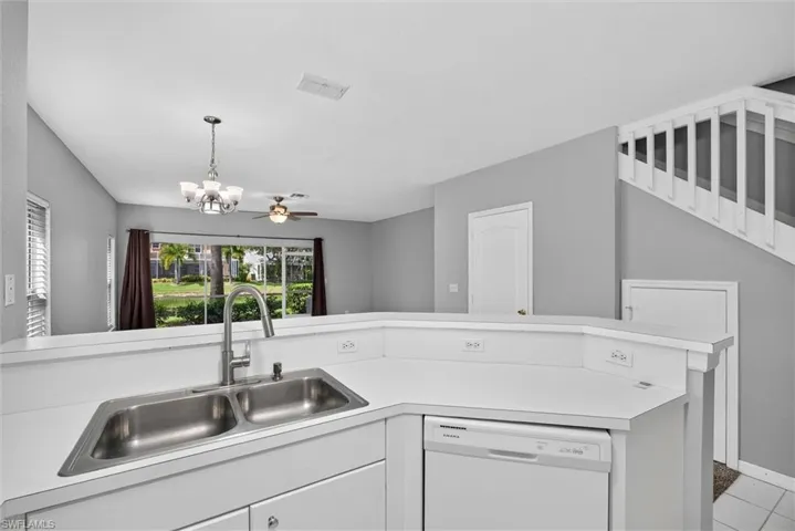 Kitchen featuring a double stainless steel sink, white countertops, and white cabinetry