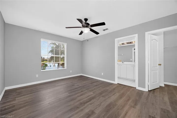 Spacious interior featuring wood-finish flooring, a ceiling fan with integrated lighting, and a large window