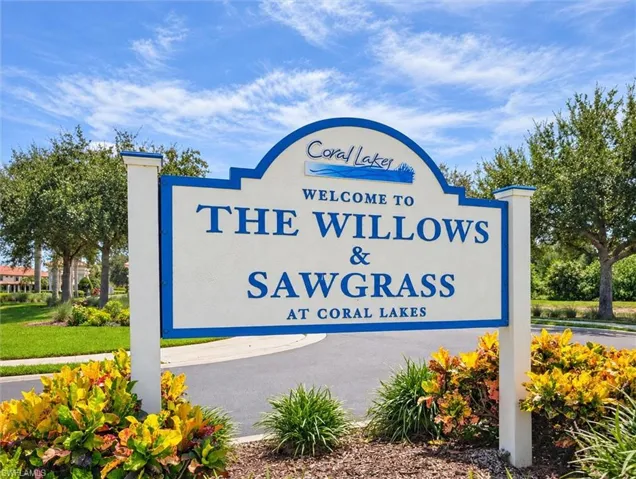 Community entry signage featuring decorative landscaping and mature trees