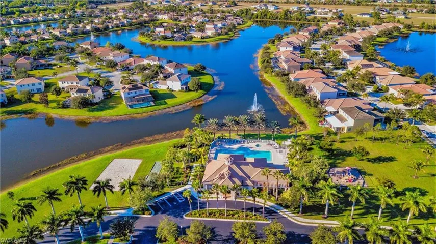 Lakeside community featuring a central clubhouse with an outdoor pool, a sand volleyball court, and a children's play area