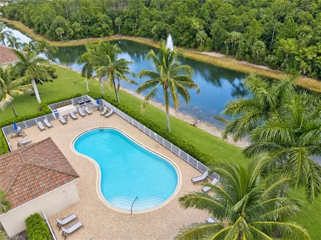 Freeform swimming pool with integrated steps, surrounded by a paved deck and a safety fence