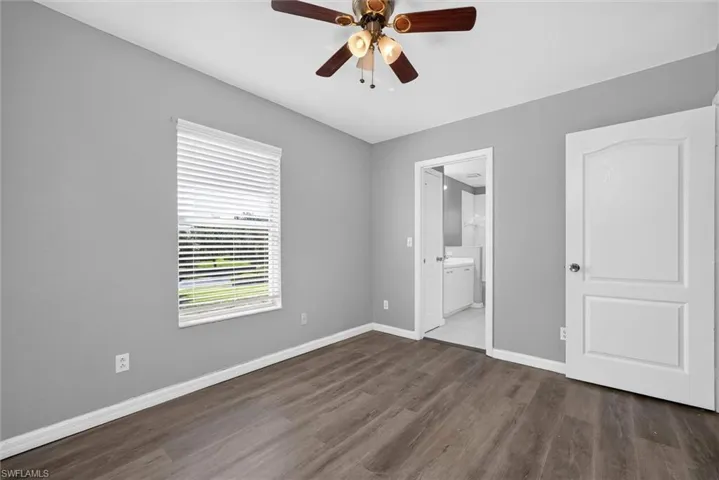 Wood-finish flooring, ceiling fan with integrated lighting, white window blinds, and paneled interior doors