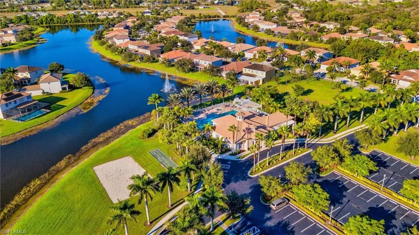 Waterfront estate nestled in a prestigious gated community featuring lush manicured landscaping, mature palm trees, and serene lakefront positioning