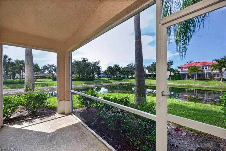 Screened lanai with textured concrete flooring, overlooking a water feature and established landscaping