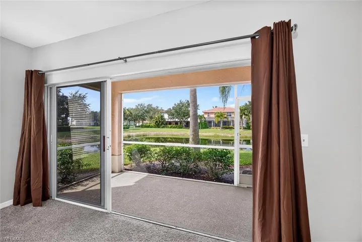 Sliding glass doors opening to a screened patio with a water feature backdrop