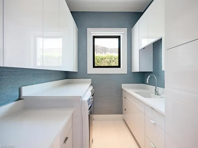 Kitchen with sink, white cabinetry, and light tile floors