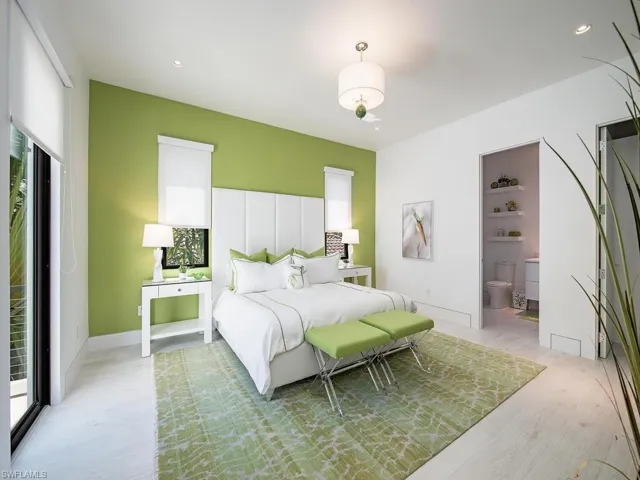 Bedroom with ensuite bath, light hardwood / wood-style flooring, and access to exterior