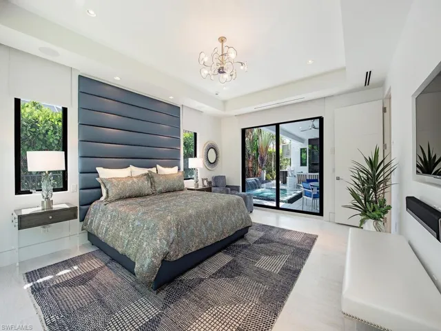 Bedroom with access to outside, a tray ceiling, wood-type flooring, and a chandelier