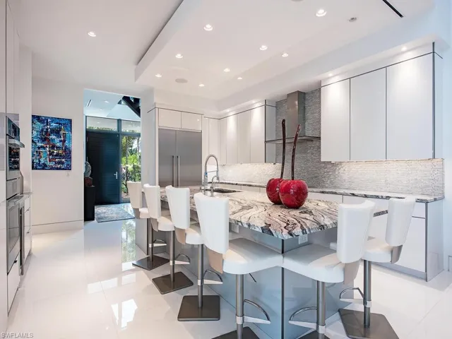Kitchen with a breakfast bar area, tasteful backsplash, stainless steel built in fridge, and light tile floors