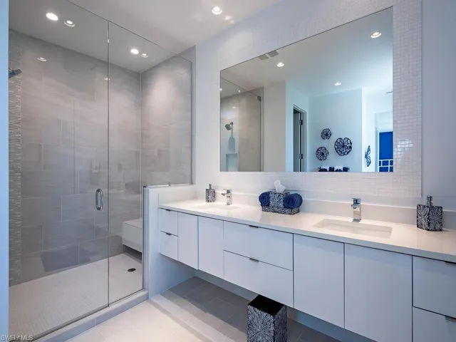 Bathroom with double vanity, tile flooring, and a shower with shower door