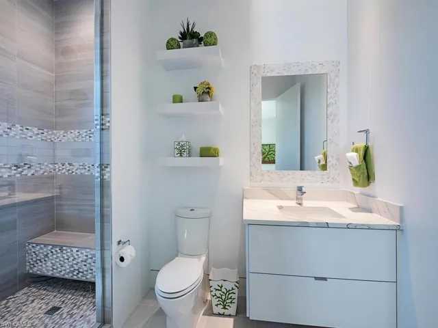 Bathroom featuring tiled shower, vanity, and toilet