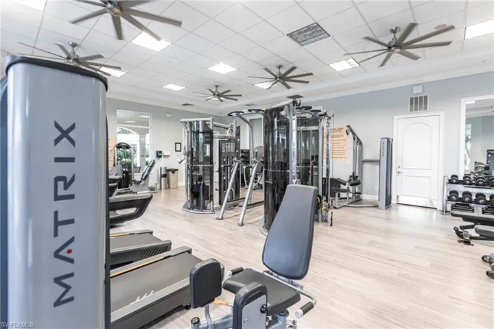 Gym featuring ornamental molding, wood finished floors, ceiling fan, and a drop ceiling