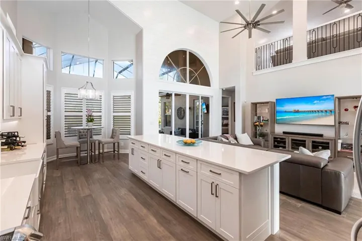 Kitchen featuring open floor plan, a towering ceiling, a ceiling fan, a chandelier, and white cabinetry