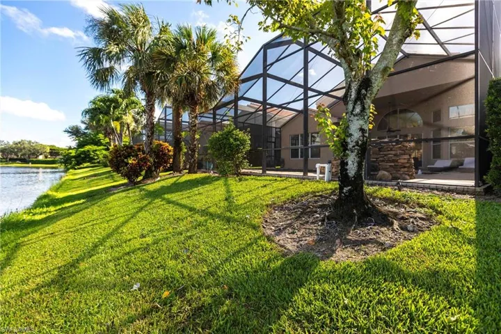View of green lawn with glass enclosure and a water view