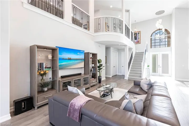 Living area featuring a towering ceiling, stairs, and wood finished floors