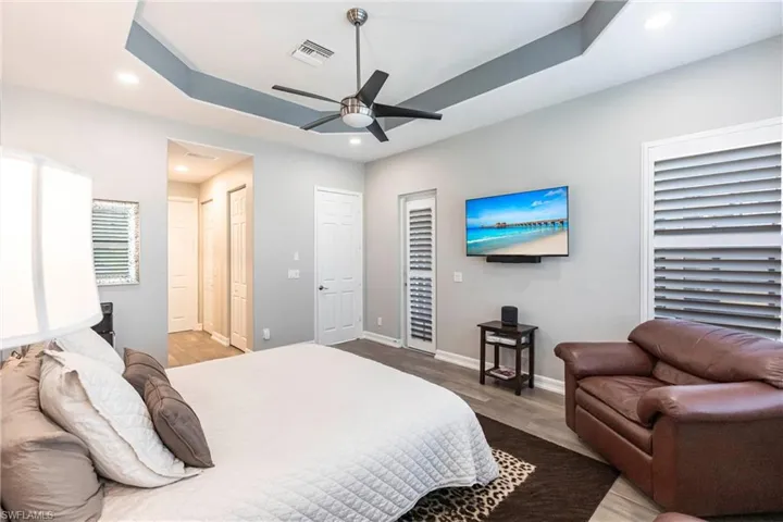 Bedroom with recessed lighting, wood finished floors, a tray ceiling, and a ceiling fan