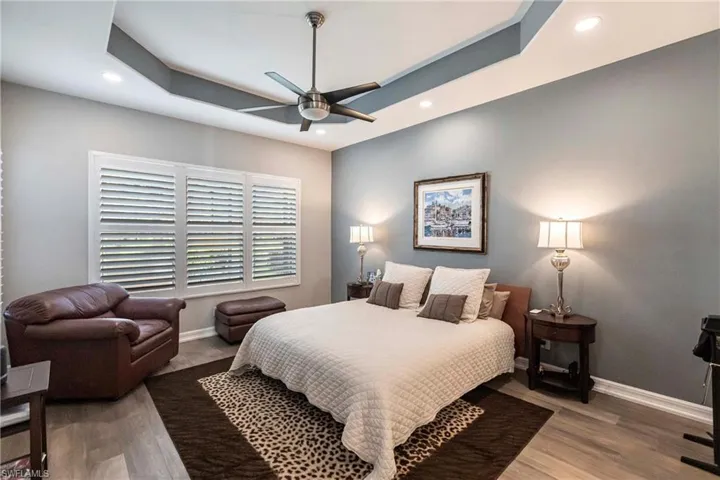 Bedroom with recessed lighting, wood finished floors, ceiling fan, and a raised ceiling
