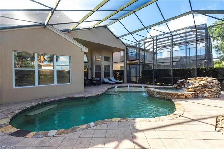 View of pool featuring a patio area, a pool with connected hot tub, and a lanai