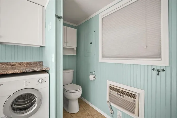 Bathroom with tile patterned flooring, a wall unit AC, crown molding, toilet, and washer / clothes dryer