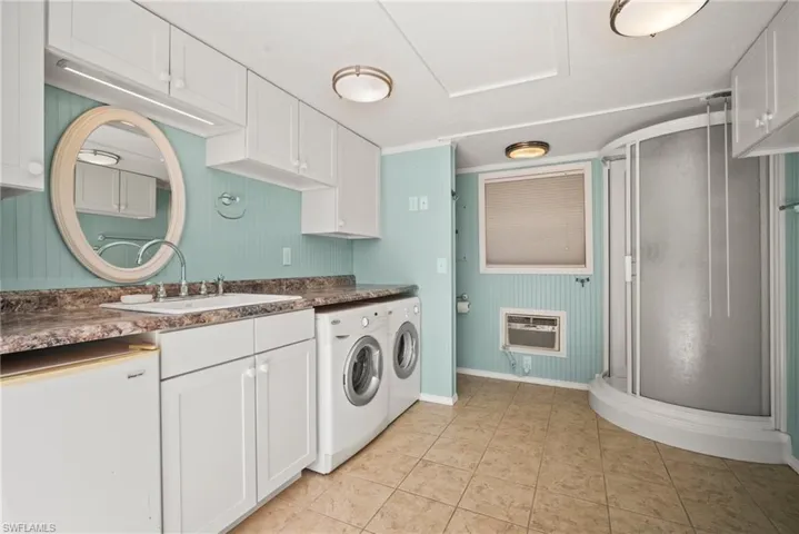 Clothes washing area with independent washer and dryer, baseboards, heating unit, a sink, and light tile patterned floors