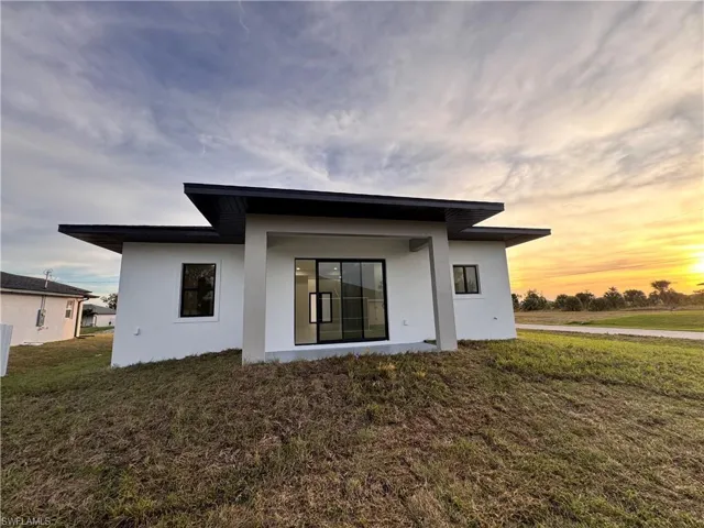 Rear view of property featuring stucco siding and a yard